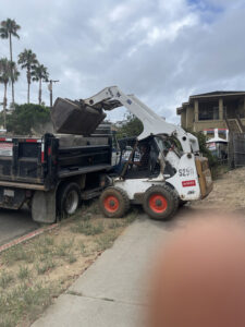 Bobcat removing concrete from failed vditch